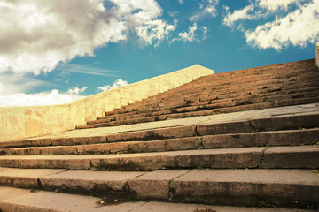 A wide stone staircase to a beautiful sky with clouds on a bright sunny day.