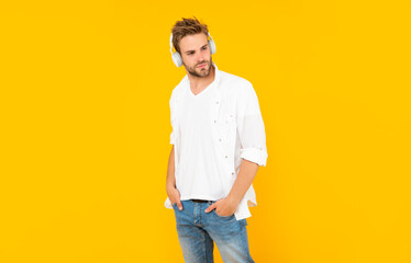 young guy with bristle listen music on yellow background, fashion
