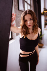 Naklejka premium Fashionable woman in black outfit looking at camera near wall at home 