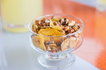 Small bowl of toasted salted corn kernels and banana chips in a Peruvian bar