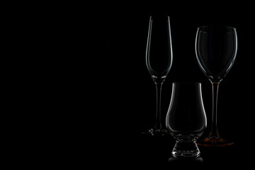 Silhouette of a champagne, wine and whisky glass in white on black background. The glasses are arranged in the right third.