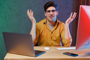Young questioned sad employee programmer IT specialist business man in casual shirt sit work at...