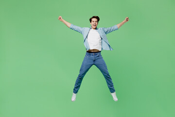 Full size body length overjoyed happy exultant young brunet man 20s years old wear blue shirt doing winner gesture celebrate clenching fists say yes isolated on plain green background studio portrait