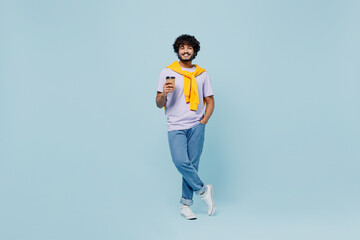Fototapeta na wymiar Full size cheerful young bearded Indian man 20s years old wears white t-shirt hold takeaway delivery craft paper brown cup coffee to go isolated on plain pastel light blue background studio portrait.