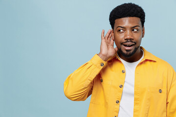 Young curious nosy man of African American ethnicity 20s wear yellow shirt try to hear you overhear...