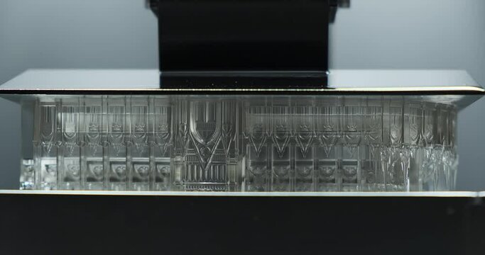 Extreme Close up front view of Resin MSLA 3D Printer moving up and down during printing object with clear resin.