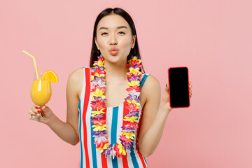 Young woman of Asian ethnicity in striped one-piece swimsuit hawaii lei hold cocktail mobile phone with blank screen isolated on plain pastel pink background. Summer vacation sea rest sun tan concept. © ViDi Studio