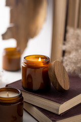 Obraz na płótnie Canvas A set of different aroma candles in brown glass jars. Scented handmade candle. Soy candles are burning in a jar. Aromatherapy and relax in spa and home. Still life. Fire in brown jar