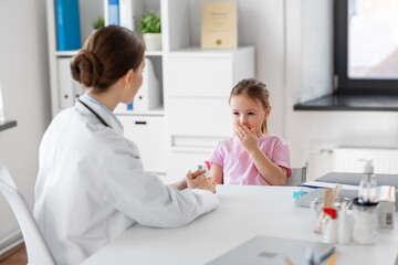 medicine, healthcare and pediatry concept - female doctor or pediatrician and coughing little girl patient on medical exam at clinic