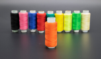 Sewing thread and bobbin in yellow color on isolated black background