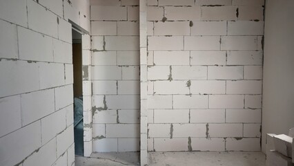 View of an unfinished room in a new apartment building with concrete and aerated concrete block walls. Finished wall of aerated concrete blocks in a new apartment.