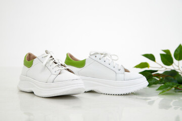 White women sneakers in the studio on white background. Fashion shooting for a catalog or store indoors