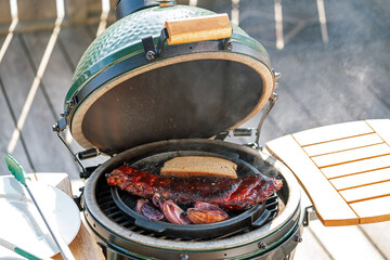 smoking spareribs and red onions on a ceramic grill with charcoal
