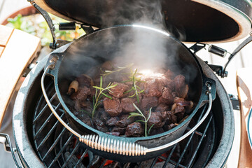 outdoor cooking - goulash from venison meat in a dutch oven on a charcoal grill at a sunny day - obrazy, fototapety, plakaty