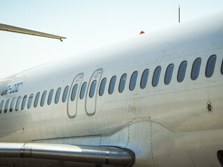 Fototapeta premium Fuselage of airplane with door and windows. Row of portholes outside the passenger aircraft. Plane on bly sky background.