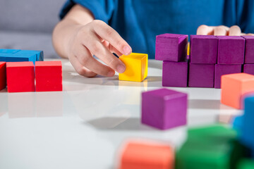 Close-up of young little toddler girl hand plays with wooden colorful toy block at home or...