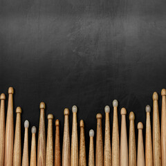 Close-up of a large group of wooden drumsticks on a black chalkboard with copy space. Percussion instrument banner.