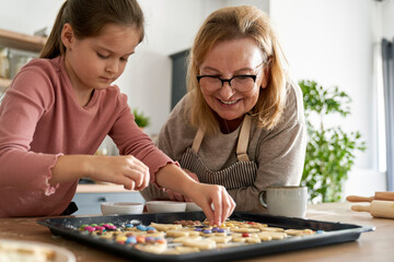 Caucasian of grandmother help her granddaughter bake cookies