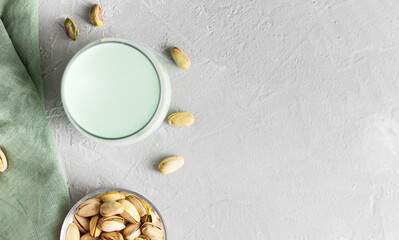 Pistachio milk in the glass on the concrete gray background, top view