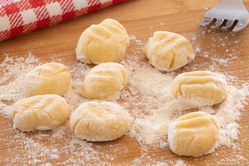 raw gnocchi on a wooden board with flour