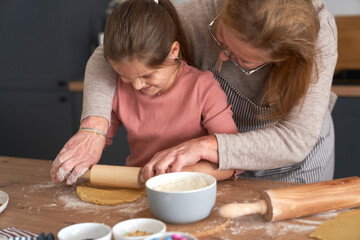 Caucasian of grandmother help her granddaughter bake cookies