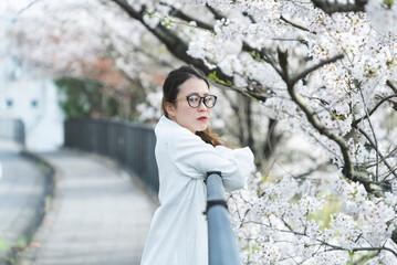 桜の花を見ながら散策する女性