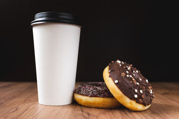 white coffee cup on dark wooden background with donuts