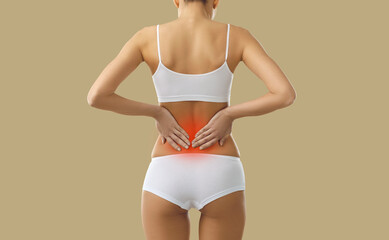 Fototapeta na wymiar Rear view of unwell woman in underwear suffer from backache. Acute pain in lower spine. Female struggle with spasm or ache in back or having kidney stones symptom. Healthcare concept.