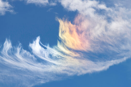 Sundog cloud formation, white and rainbow colours against a blue sky, ice crystal formation prism effective 


