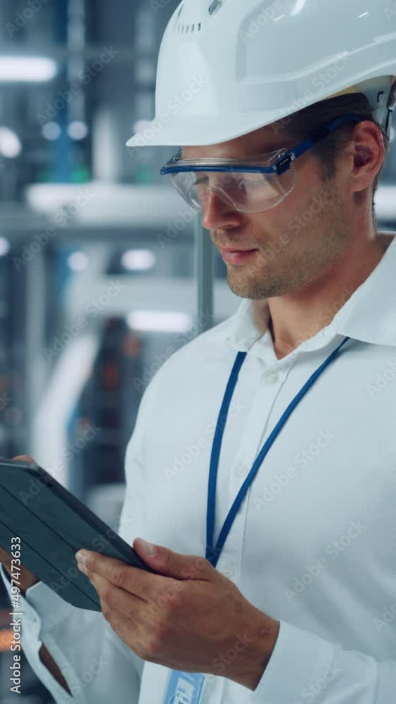 Poster vertical portrait of male engineer in safety goggles and hard hat using tablet computer at a car ass