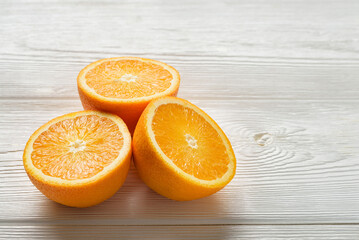 Three halves of juicy oranges on a white wooden table.