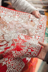 hand holding a Red and silver lace fabric 