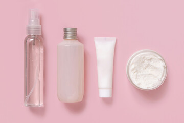 Homemade Cosmetics in plastic tubes and bottles on pink top view. Brand packaging mockup.