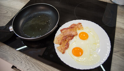 Making fried eggs and bacon for breakfast
