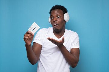 African young man with a retro cassette does not know what to do with it.