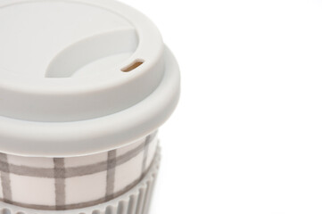 Checkered ceramic cup with rubber lid, shot against a white background.