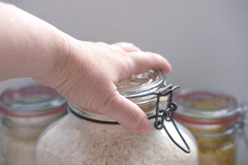 close-up of female hand closes the lid of a rice jar, the concept of food strategic stocks for a rainy day, food supplies for cooking, ecological packaging, pest control