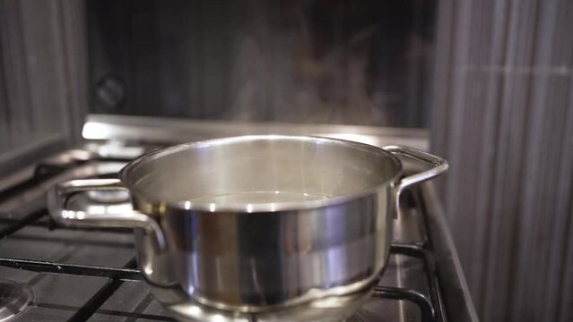 steam rises above a pot of boiling water. cooking broth, soup or dumplings on the stove. slow motion.