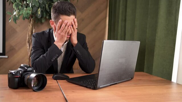 Arab male photographer in a jacket throws off a photo on laptop and is disappointed. concept computer virus destroyed data on hard drive