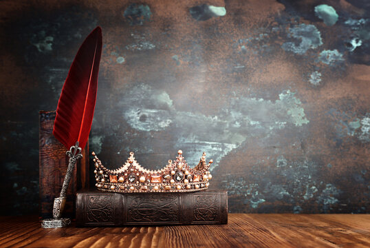 low key image of beautiful queen or king crown and old book. fantasy medieval period