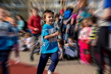Young preschool children, running on track in a marathon competition, radial blur motion