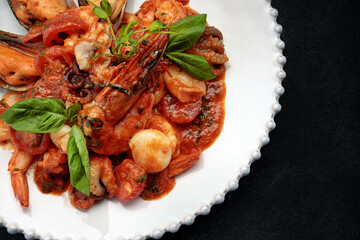 Sauteed seafood on a white plate, on a dark background