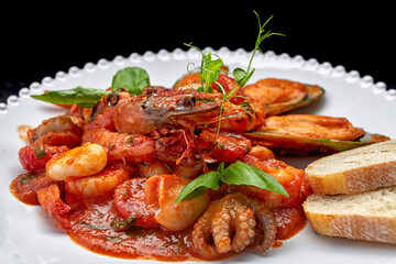 Sauteed seafood on a white plate, with toasts on a dark background