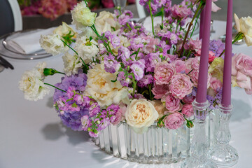 Beautiful restaurant table decor for violet wedding. Colorful flowers and candles decoration for celebration