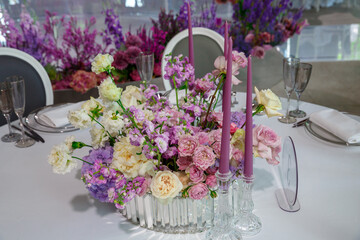 Beautiful restaurant table decor for violet wedding. Colorful flowers and candles decoration for celebration