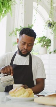 Vertical video of african american male barista preparing coffee in cafe