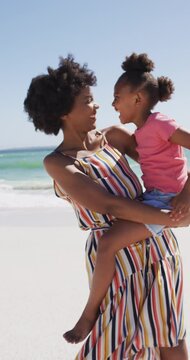 Vertical video of happy african american mother with daughter at beach
