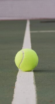 Vertical video of yellow tennis ball and net on tennis court