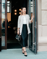 attractive young woman coming out of a small cafe.