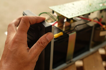 Closeup of a man doing UPS battery repair with stabilizer for home PC. Equipment for computer...
